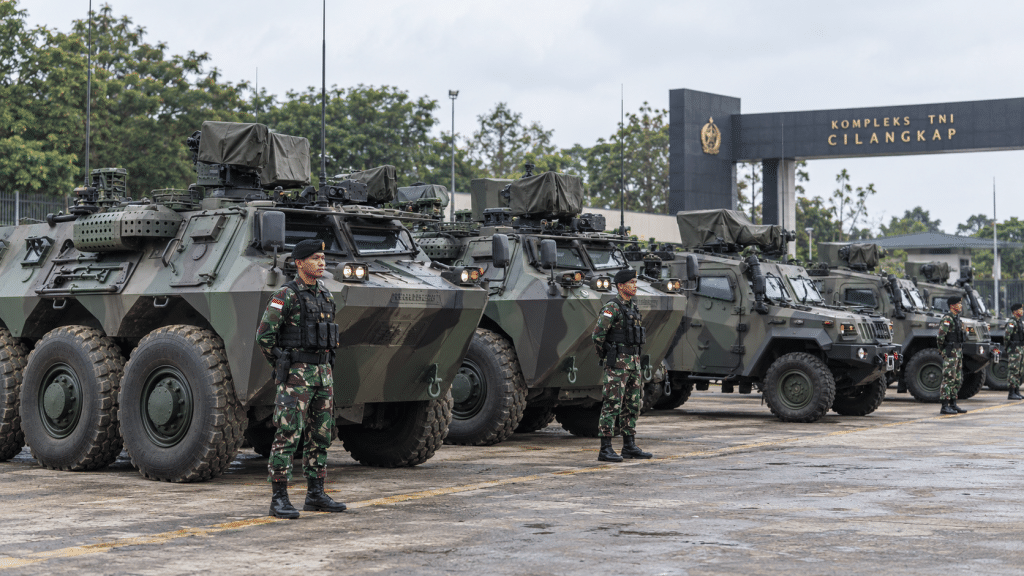 Barisan kendaraan tempur lapis baja Panser Anoa dan sistem artileri terparkir statis dalam kesiapan operasional di area pangkalan.